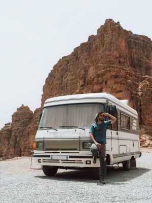 Man standing by a camper against stunning eroded rock formations. Perfect for travel and adventure themes.